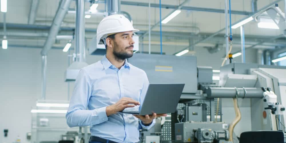 Chief Engineer in the Hard Hat Walks Through Light Modern Factory