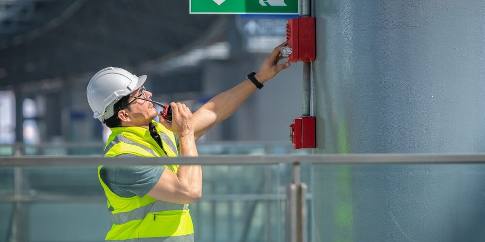 Engineer wearing safety unifrom and helmet under checking fire alarm emergency system